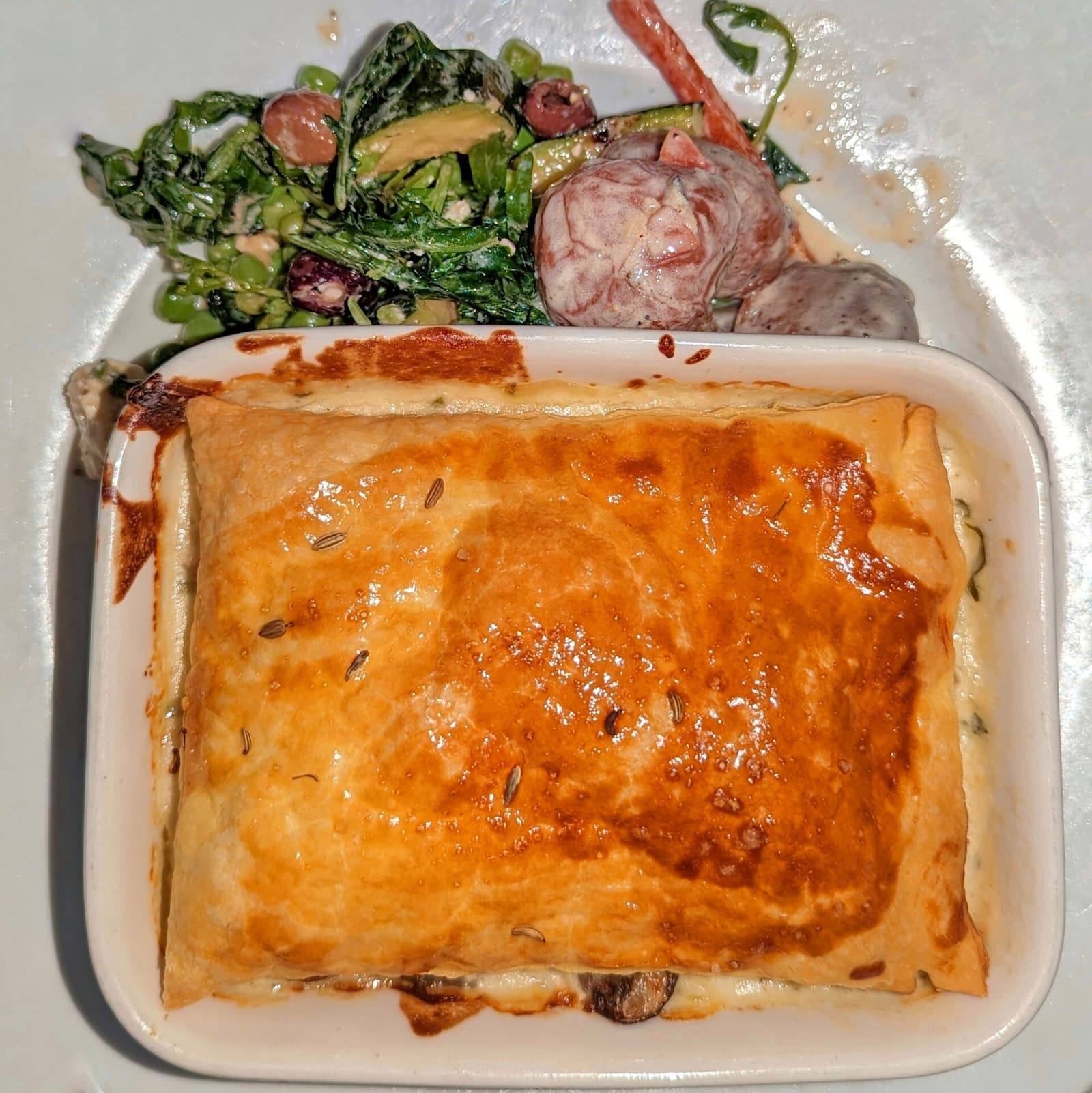 A pie with a golden, glazed pastry lid in a white rectangular baking dish.