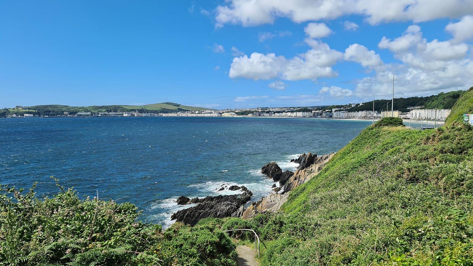 Looking across a bright blue Douglas Bay from grassy, gorse-covered cliffs above Port Jack.
