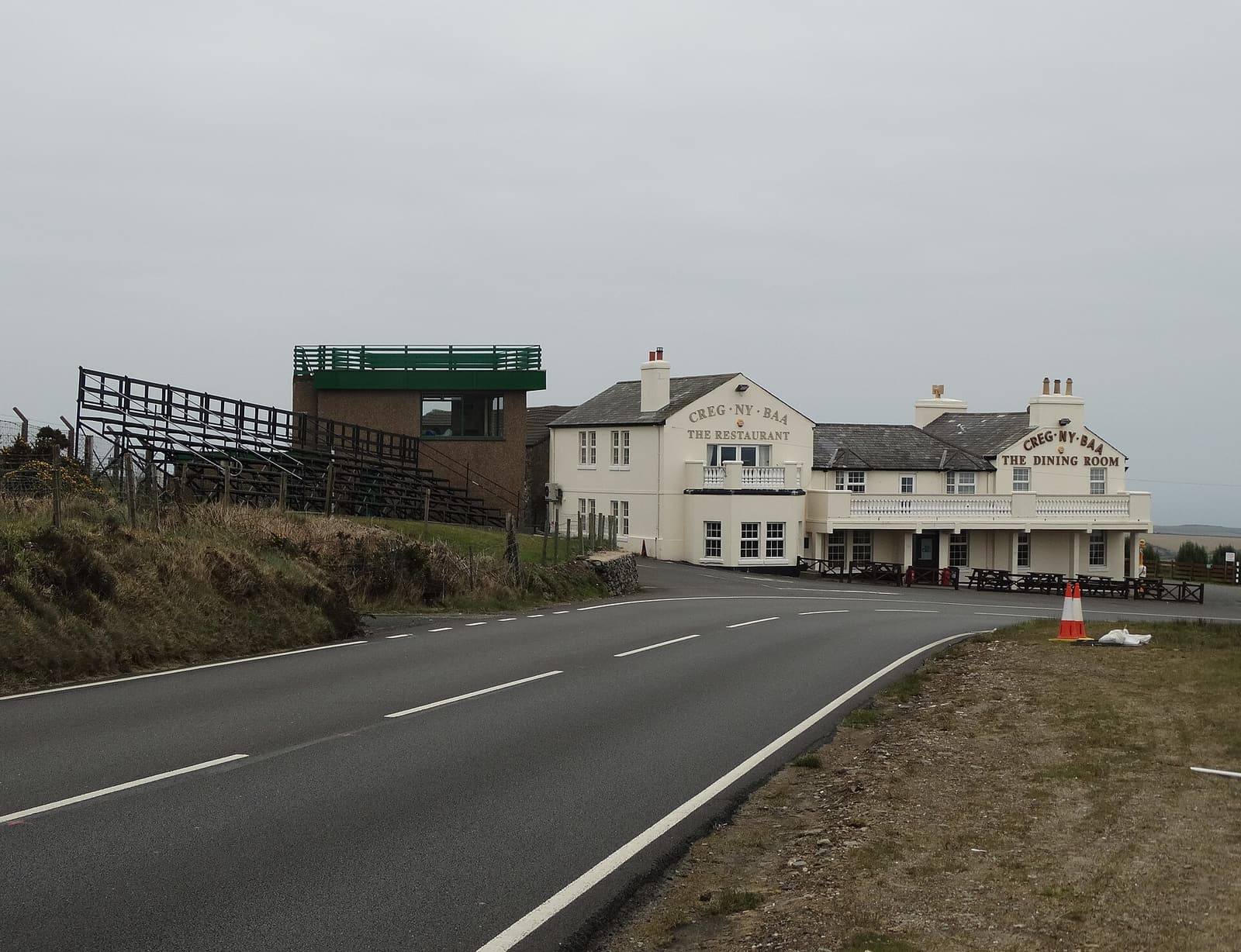 The road sweeping round the Creg ny Baa corner on the TT Mountain Course, with the white Creg ny Baa inn beside it.